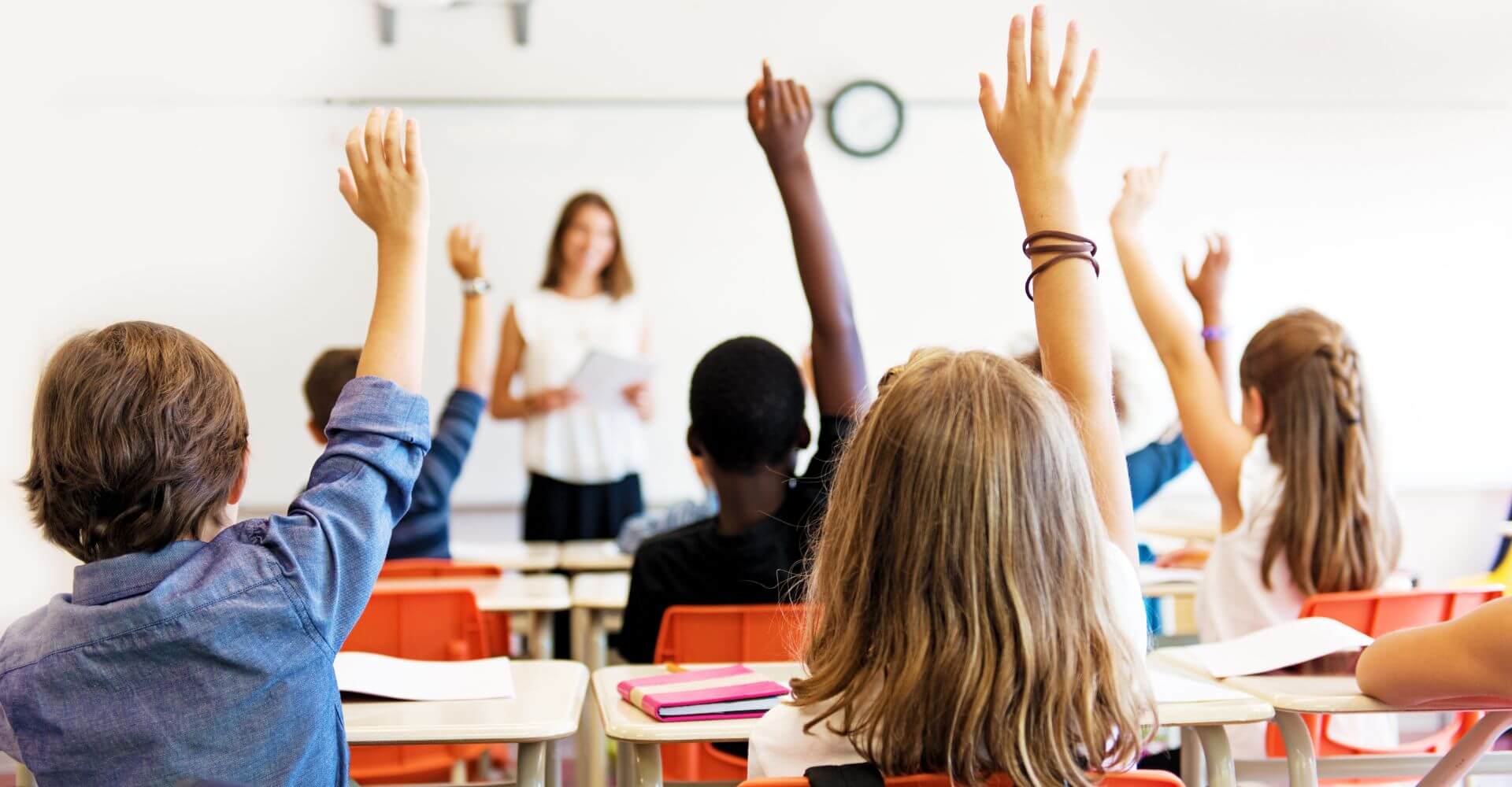 students raising their hands in the classroom