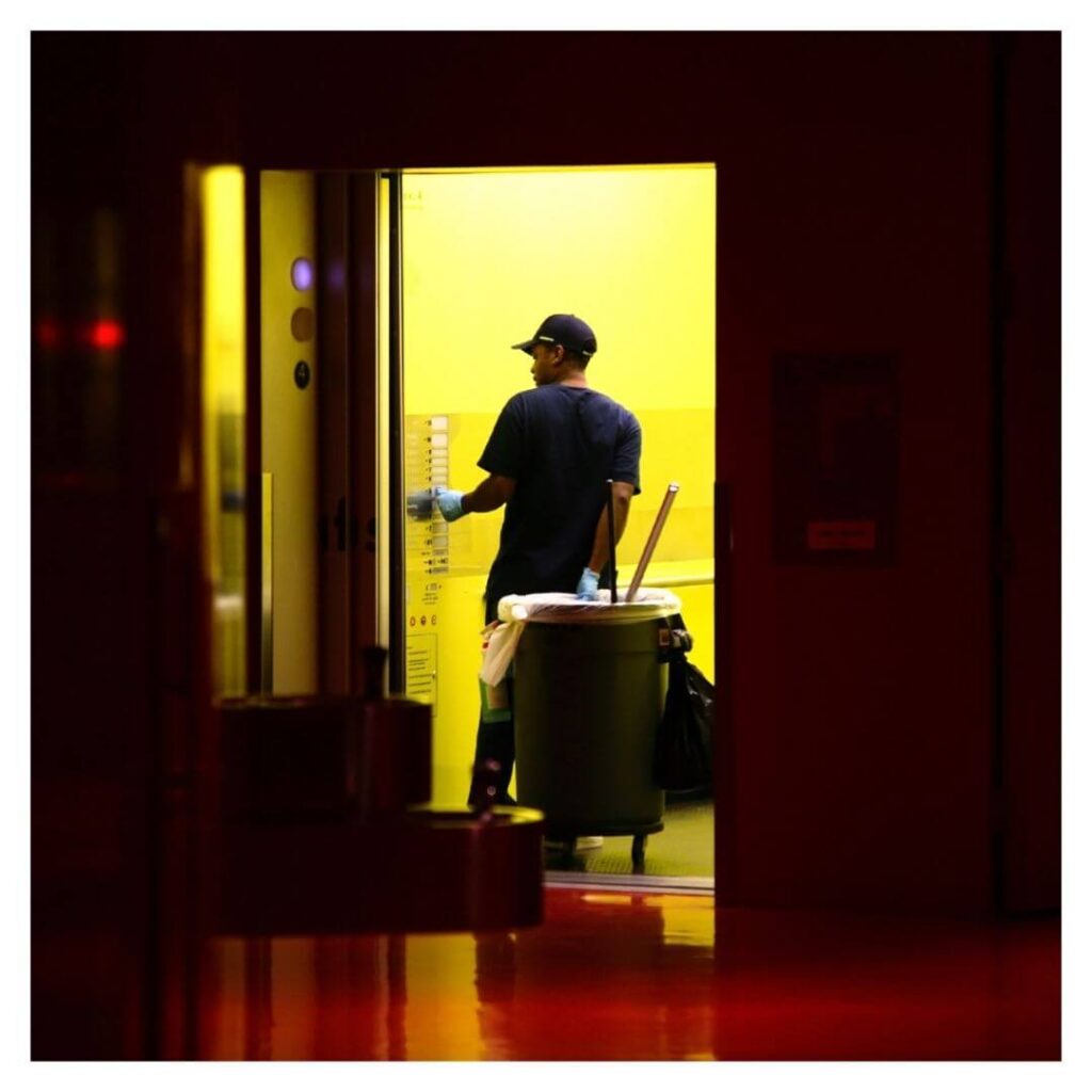 person rolls a commercial trash can through a doorway