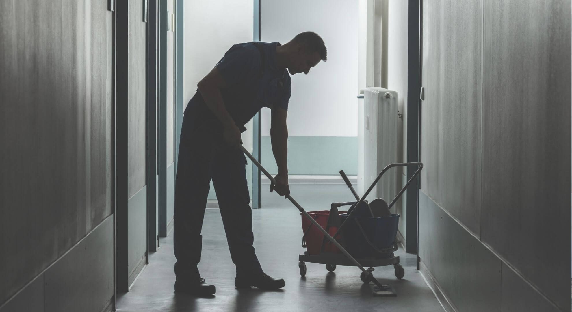 person uses a mop bucket while cleaning a floor