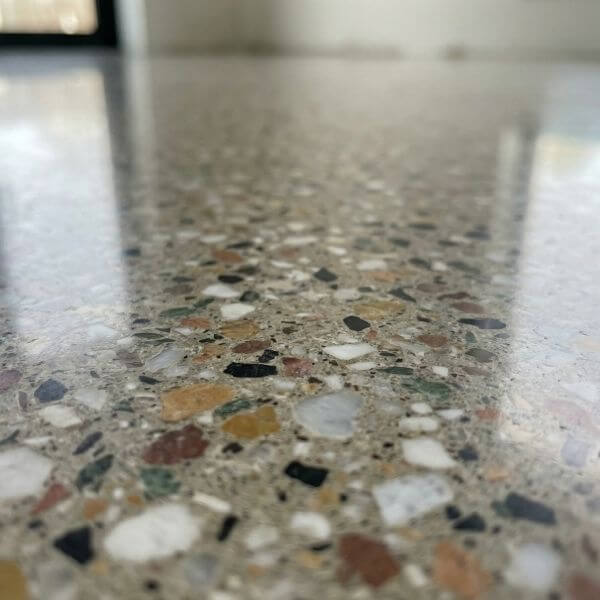 A close-up detail shot of a newly polished terrazzo floor surface showing aggregate texture and reflections.